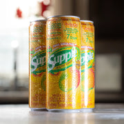 Three cans of Supple Drink on a surface with a blurred background